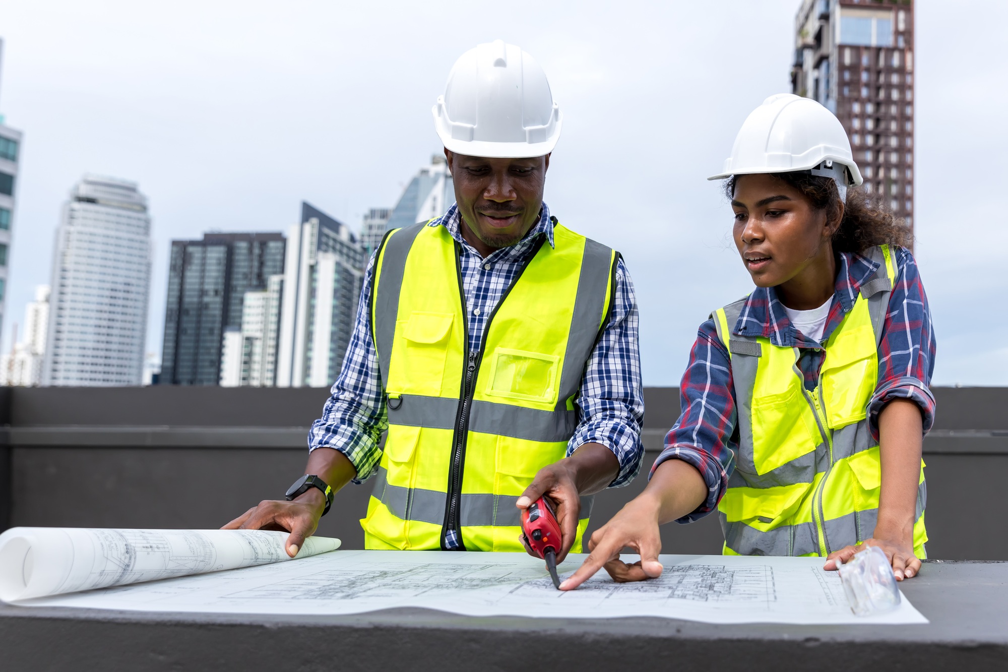 Engineers with draft plan of building on constructing site. Engineer working on building site.